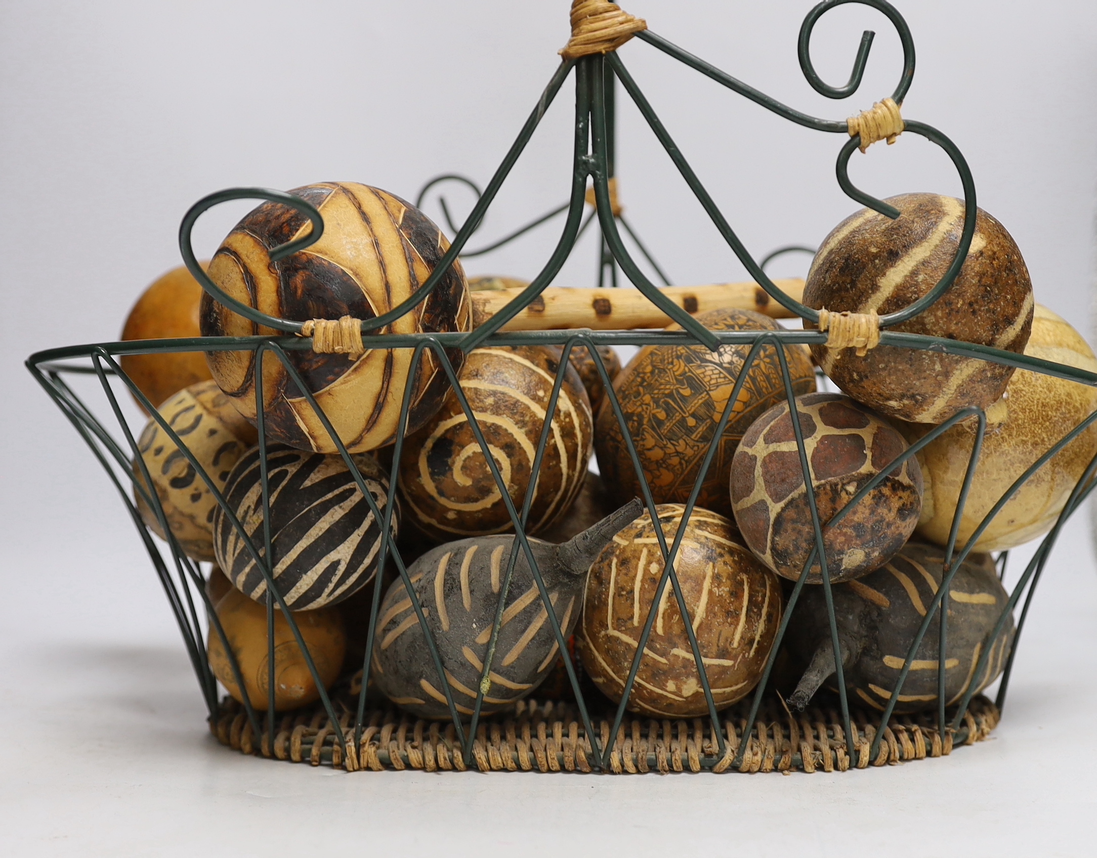 A wirework basket, containing assorted decorated gourds, nuts from Indonesia etc.